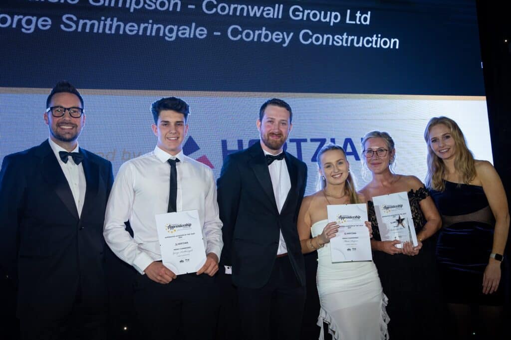 Sarah Hyde-Wear and two highly commended nominees on stage receiving their awards from sponsor Hertzian, presenters Holly Day and Neil Caddy stand either side of the group.