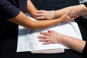 A close up of a student giving a hand massage to a client.