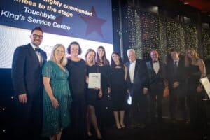 Eight members of staff from Hiyield collect the SME Employer of the Year award on stage with presenters Holly Day and Neil Caddy at either end of the group.