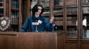 A young man stands at a podium in a debate.