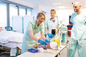 Nurses in a nursing simulation suite work with a dummy