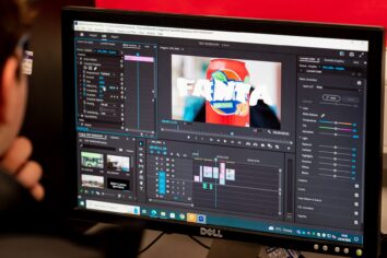 The camera looks over the shoulder of a student who is using Adobe premier pro to edit a video which features a fanta can.