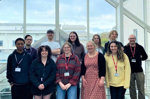 A group of access students stand in front of a large window at the University Centre Truro and Penwith.