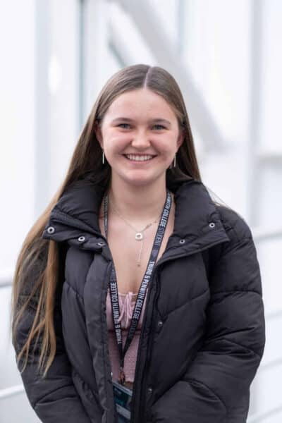 Poppy Maths student wearing a dark coat and lanyard.