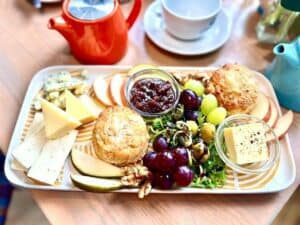 A grazing platter in a cafe comprising of cheeses, grapes and crackers.