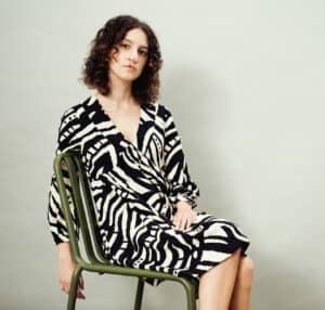 Student in black and white zebra print dress models on a green chair.