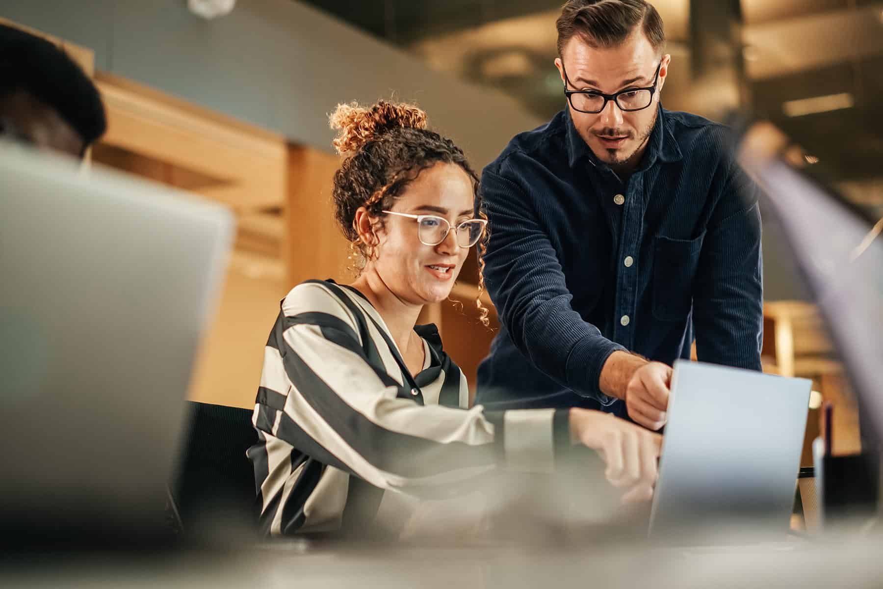 Two Colleagues Working On Laptop In Office