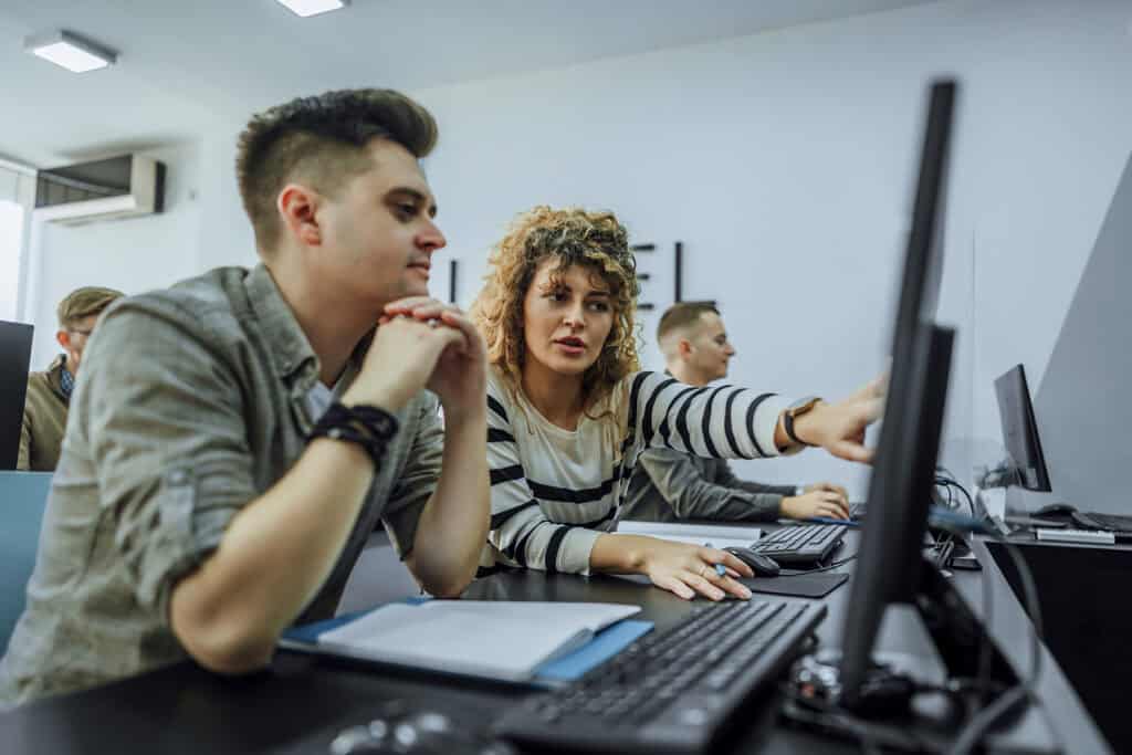 Cheerful students discussing their tasks in the computer lab