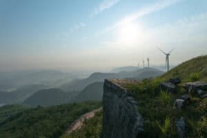 A grassy mountain with windmills in the background.