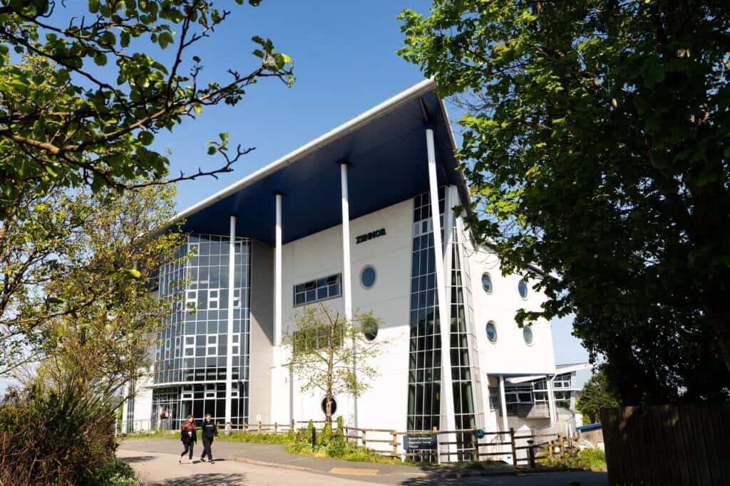 A photo of the front of the Zennor building at Penwith College. It is a sunny day and there are students walking in front of the building.
