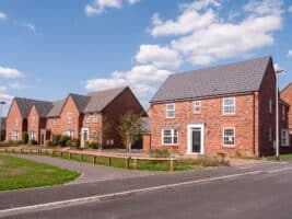 A row of new build houses. They are red brick with large windows and driveways.
