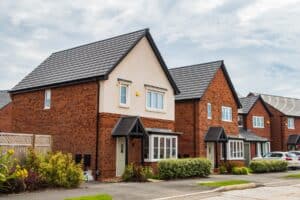 A row of Detached Houses In Manchester. Cars are parked out front.