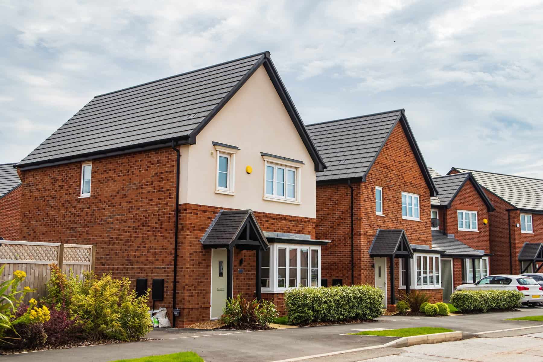 A row of Detached Houses In Manchester. Cars are parked out front.