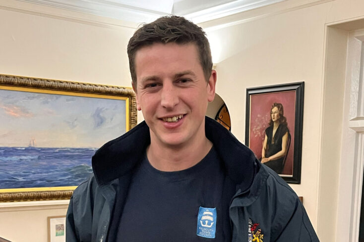 A picture of Jack holding his ILM certificate in a room full of portraits.