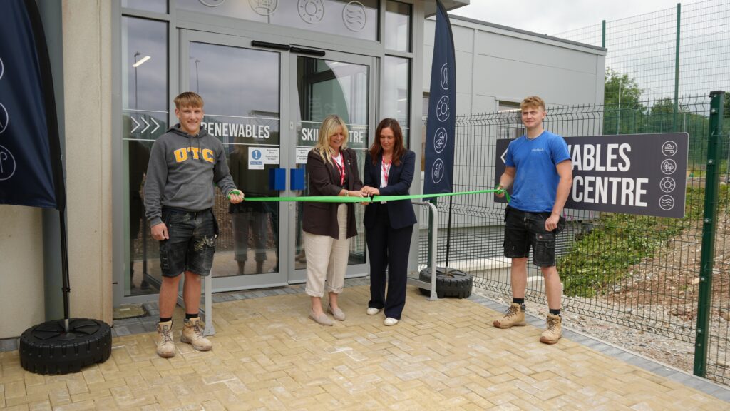 Dignitaries cutting the ribbon at the opening of the Renewables Skills Centre, with two construction students