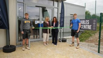 Dignitaries cutting the ribbon at the opening of the Renewables Skills Centre, with two construction students