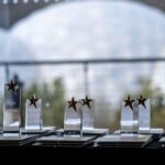 The trophies from the Cornwall Apprenticeship Awards 2024 are lined up in front of a window which shows the Eden Project's biomes.