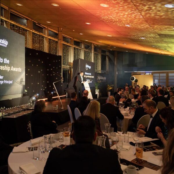 A shot of the room and stage set with two huge screens as the College Principal Martin Tucker opens the event.