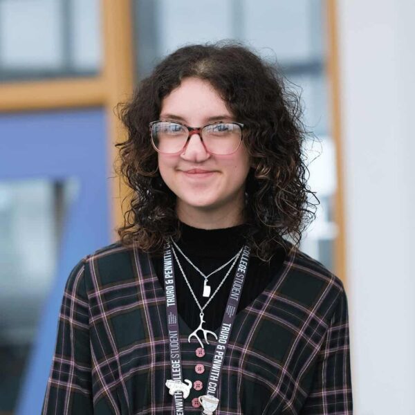Student, Bo, has curly dark hair, is wearing a lanyard with silver jewellery and is smiling at the camera.