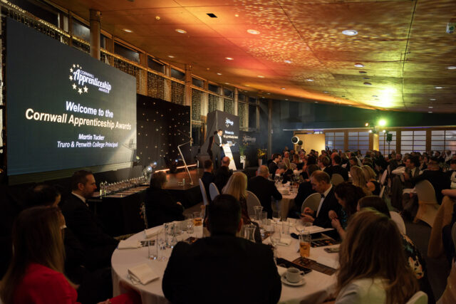 A view of the room at the Cornwall Apprenticeship Awards. Guests look towards the stage where Principal Martin Tucker is giving a speech.