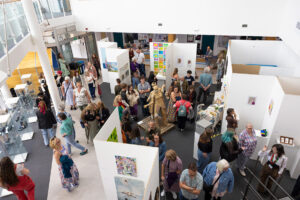 Large displays of student artwork is set up in the Fal buidling. Lots of guests are moving around the artwork on display.