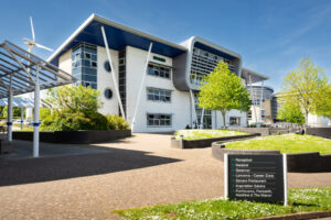 A picture of the Sennen building at Penwith College on a sunny day. You can see the exterior of the building, a pathway and a directional sign.