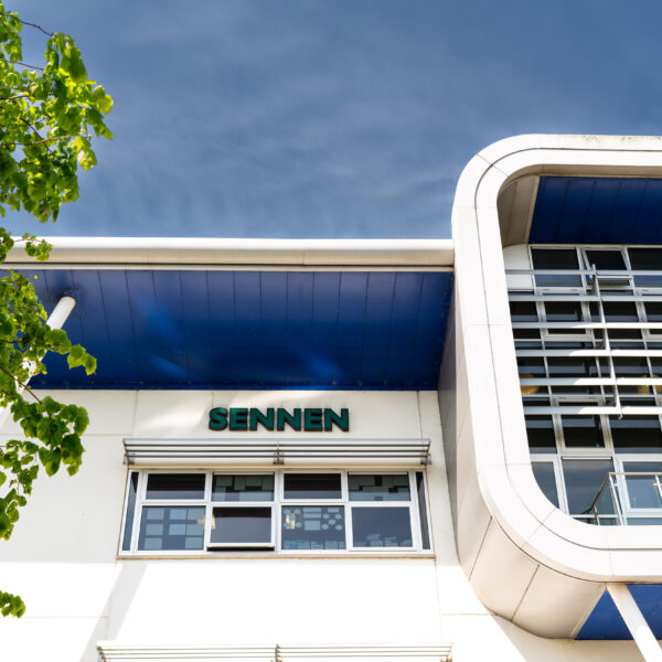 A photo of the outside of the Sennen building. You can see the building name, a part of a tree and the blue sky.