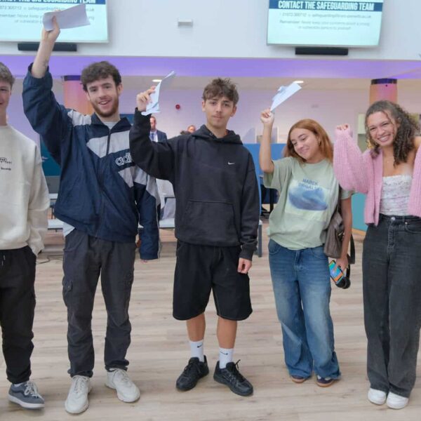 Five students hold their results above their heads on results day.