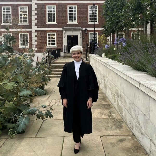 A photo of a woman dressed in formal clothing as a lawyer. She smiles at the camera.