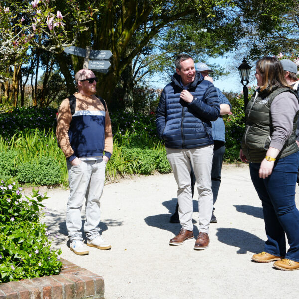 A group of people stand in the Heligan gardens on a sunny day.