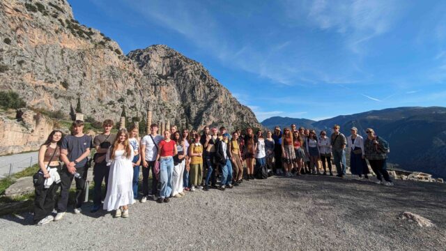 A group photo of the classical civilisation students at Rome. There are ruins behind them and a large blue sky.