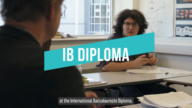 A video thumbnail for the IB Diploma video. The subject name is in the centre of the screen with 'at the International Baccalaureate Diploma' subtitled at the bottom. The background image is of a student talking to a member of staff.