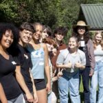 The IB diploma group stand together and smile at the camera.