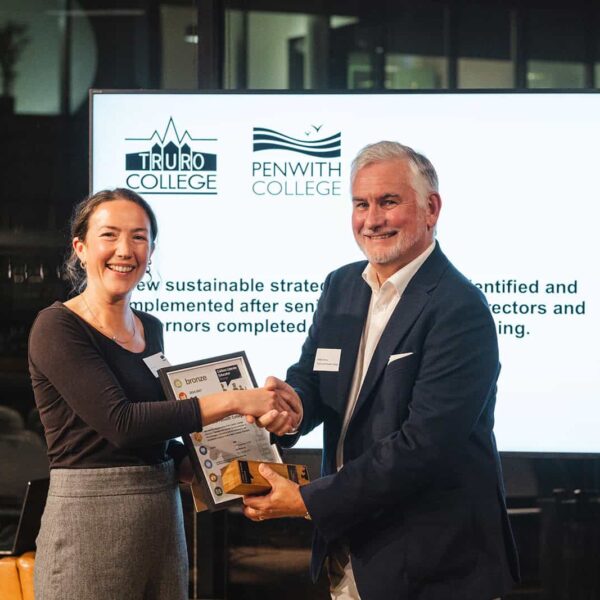 An award and certificate is presented to Simon Evans. He shakes hands with the person handing over the award.