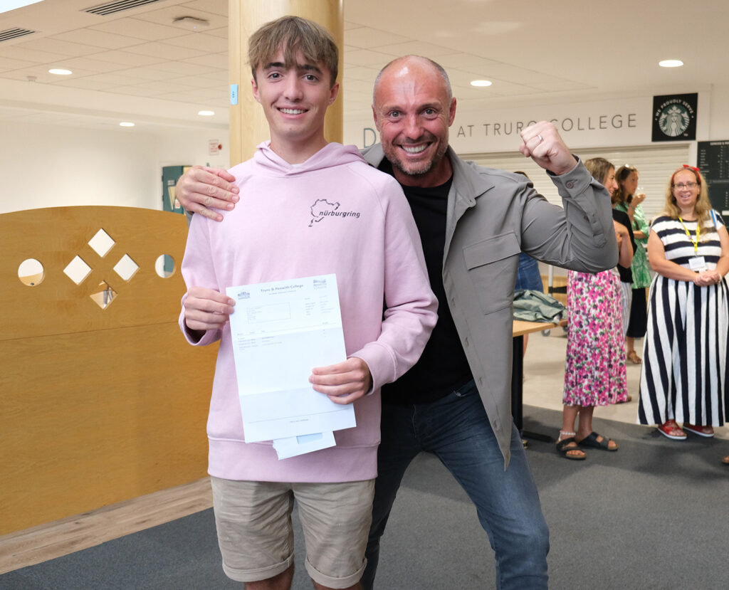 A student holds up their results with their parent.