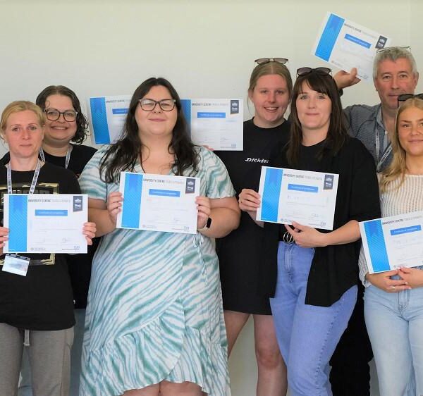 A group of students hold up certificates.