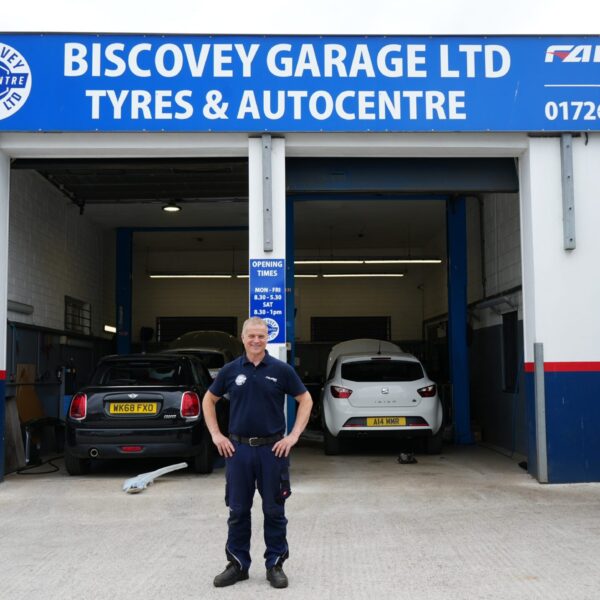 A man stands outside of the Biscovery Garage with his hands on his hips.
