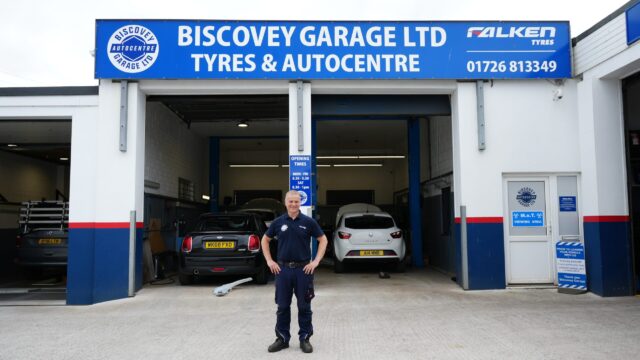 A man stands outside of the Biscovery Garage with his hands on his hips.
