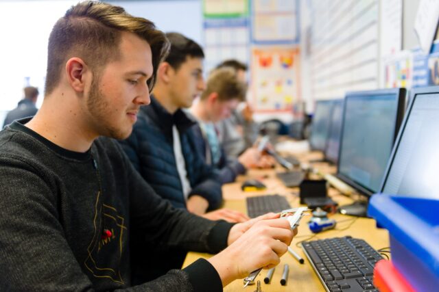 Students sat at computers who are also measuring small metal objects.