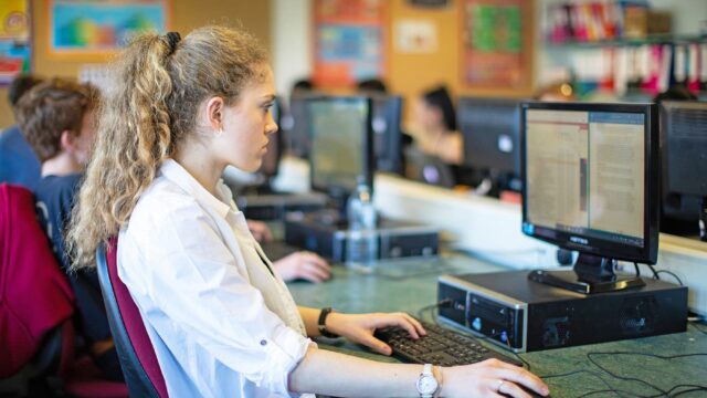 A student sat in a computer room looking at text on a computer screen.