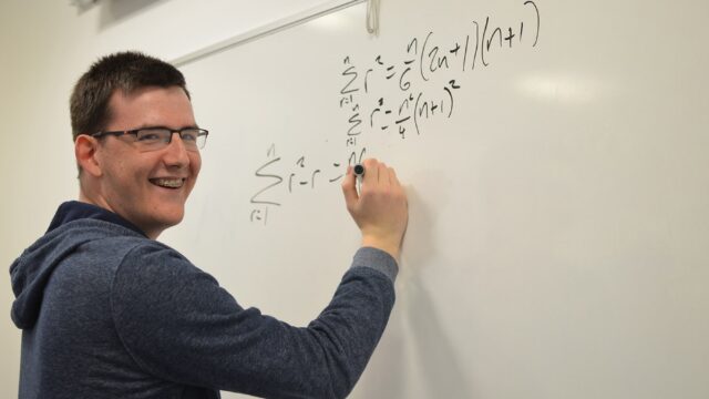 A student writing equations on a whiteboard.