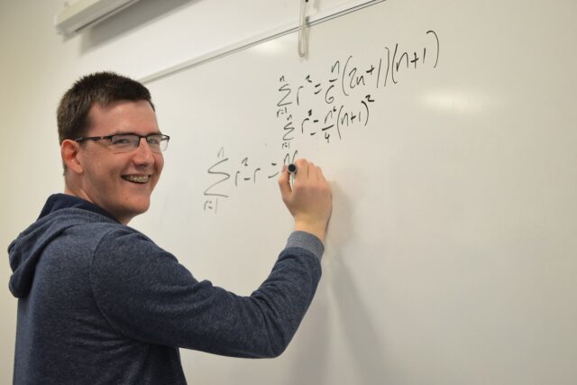 A student writing equations on a whiteboard.