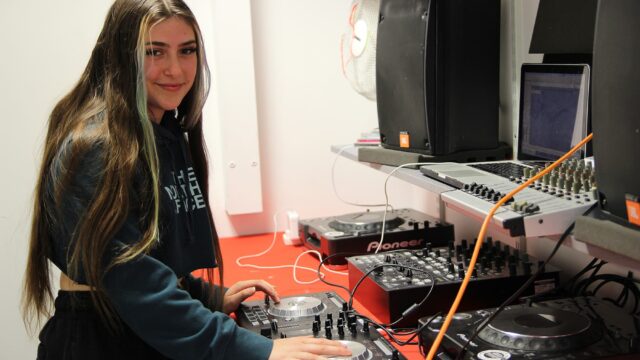 A student using music technology equipment in a studio.