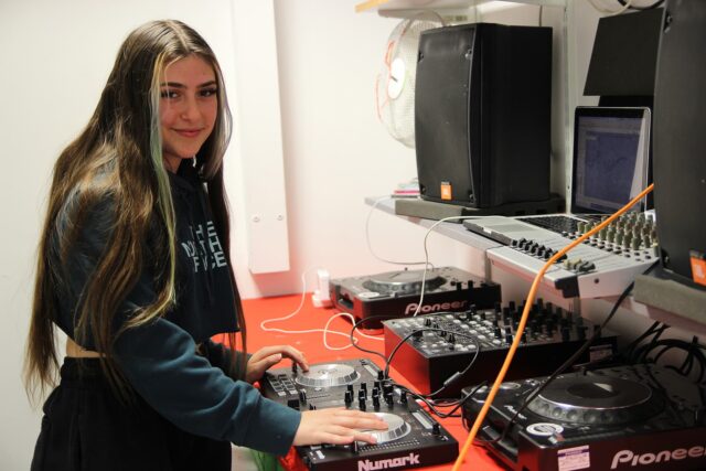 A student using music technology equipment in a studio.