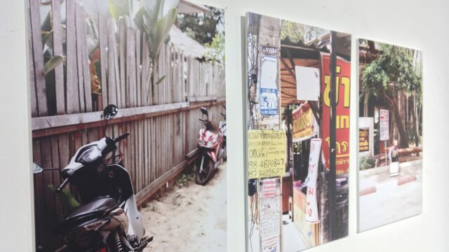 Photographs of motorcycles and markets on a large white wall.
