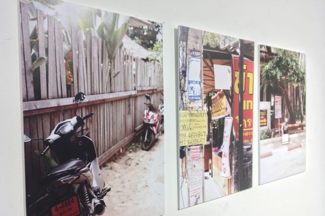 Photographs of motorcycles and markets on a large white wall.