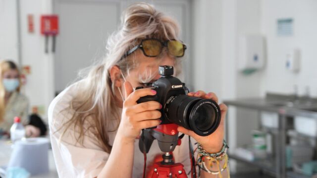 A student looking through a lens of a canon camera.