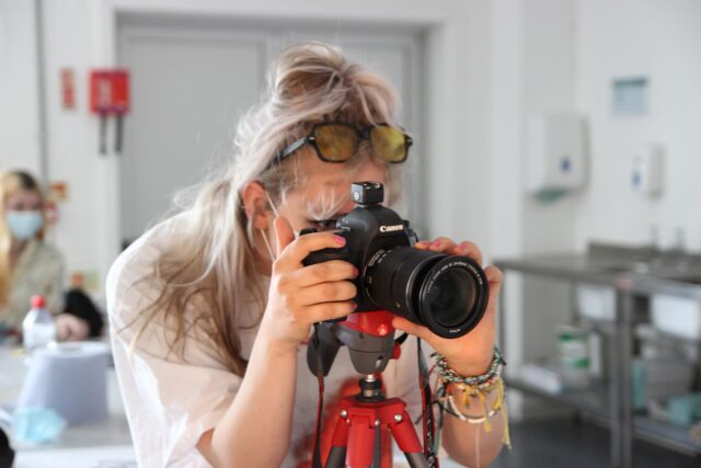 A student looking through a lens of a canon camera.