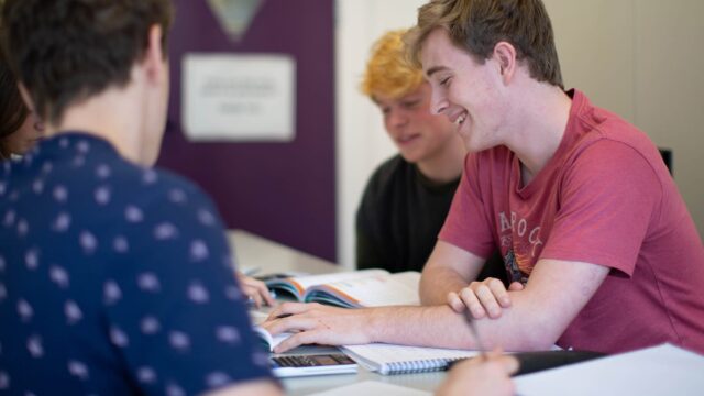 Students sat at classroom tables with text books, note books and calculators.