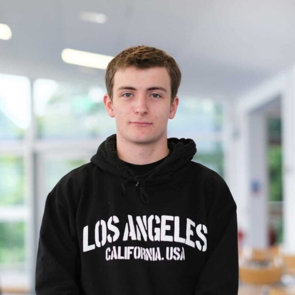 Aaron is wearing a black hoodie that says Los Angeles California USA. The background is blurred.